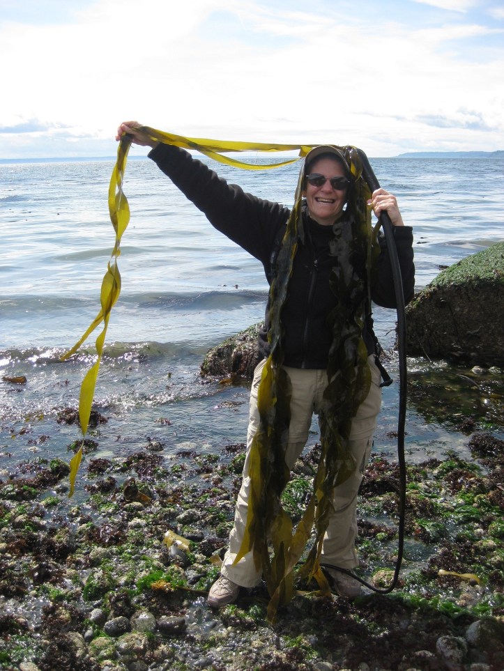 Woman at beach holding kelp over head